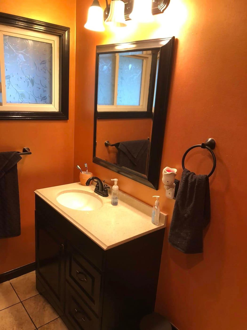 Updated bathroom with orange walls and dark vanity