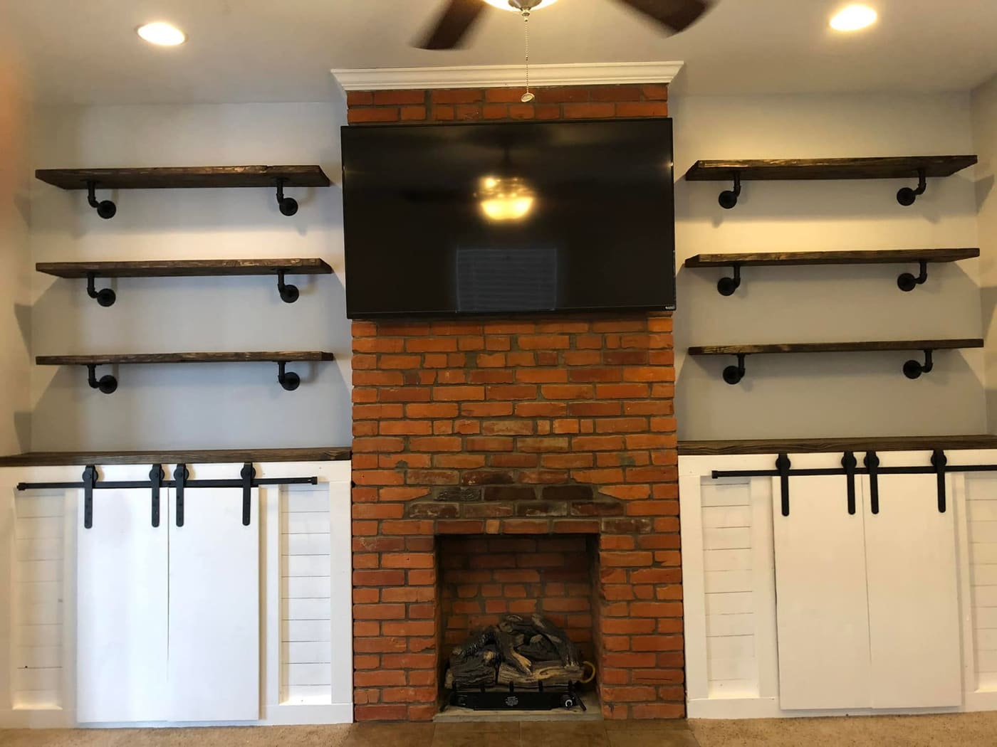 Built-in cabinets and shelves beside a brick fireplace, view 4