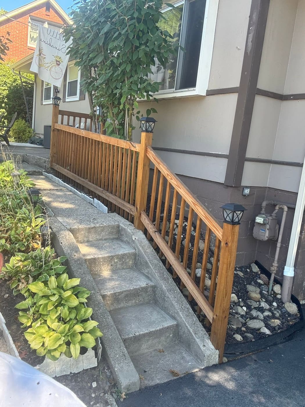 Stained wood stair railing beside garden steps, view 2